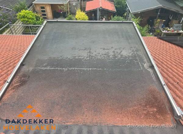 Verouderd plat dak met slijtage tussen schuine daken in Hoevelaken Verouderd plat dak met slijtage tussen schuine daken in Hoevelaken