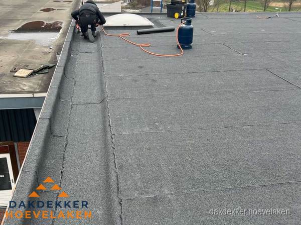 Dakdekker repareert bitumen dakbedekking op groot plat dak in Hoevelaken